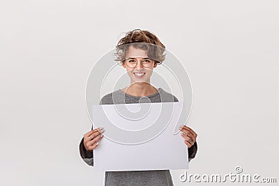 Smiling young woman with eyeglass holding empty blank paper board with copy space for text. Stock Photo