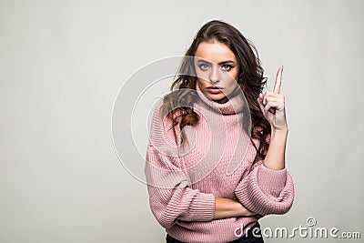 Smiling young woman pointing finger up over gray background Stock Photo