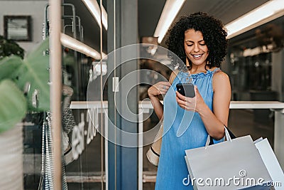 Smiling young woman reading a cellphone text while out shopping Stock Photo