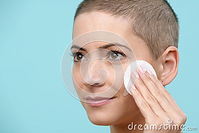 Smiling young woman removing make up using a cotton pad. Beauty and Skincare concept. Stock Photo