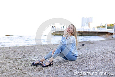 Smiling young woman rests on beach and poses in camera, sitting Stock Photo