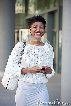 Smiling young woman sending text message int he city Stock Photo