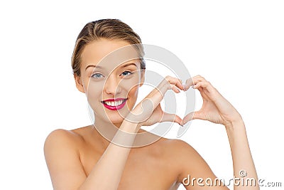 Smiling young woman showing heart shape hand sign Stock Photo