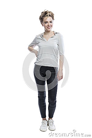 Smiling young woman is standing. Beautiful blonde in black leggings, a gray t-shirt and white sneakers. Positivity and happiness. Stock Photo