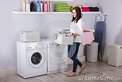 Woman Standing Near Washing Machine With Basket Of Clothes Stock Photo