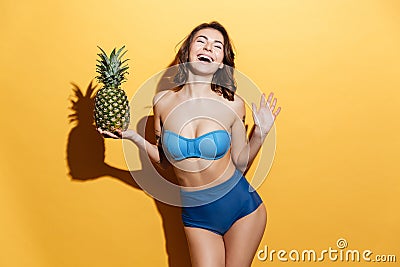 Smiling young woman in swimwear holding pineapple. Stock Photo