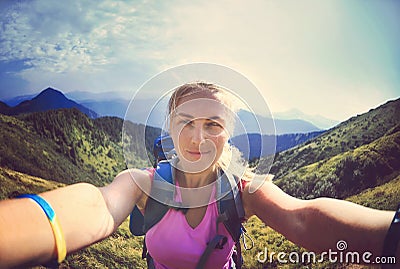 Smiling young woman takes a selfie on mountain peak Stock Photo