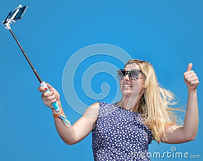 Smiling young woman taking selfie with smartphone on beach Stock Photo