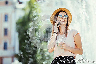 Smiling young woman teenager talking phone on summer street drinking mojito outdoor sunlight Stock Photo