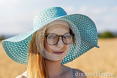 Smiling young woman wearing turquoise summer hat is posing in the sunny day Stock Photo