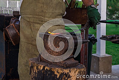 The smith holds a metal bar heated to melting on the anvil, before hammering. Retro work., Craft. Horizontal frame Stock Photo