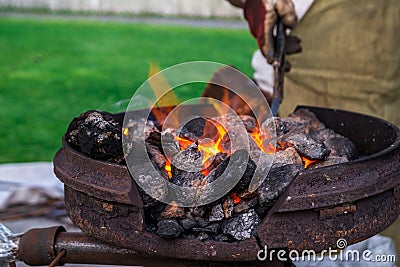 The smith melts the metal product in the boiler on the street. Retro work., Craft. Horizontal frame Stock Photo