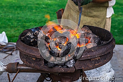 The smith melts the metal product in the boiler on the street. Retro work., Craft. Horizontal frame Stock Photo