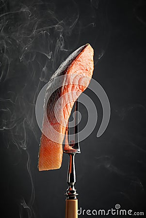 Smocked salmon piece with natural smoke on a black background Stock Photo
