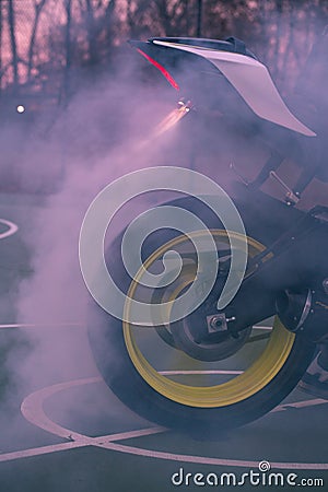 Smoking tire from motorcycle burnout with woods background Stock Photo