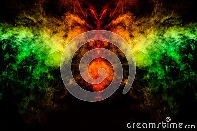 Smoke of different green, yellow, orange and red colors in the form of horror in the shape of the head, face and eye with wings on Stock Photo