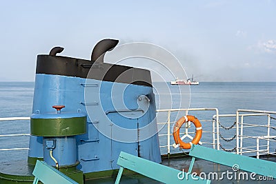 Smoke from ferry boat flue during sea with sunlight, sea water and clear sky in background, Thailand Stock Photo
