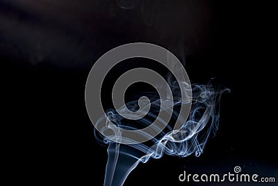 Smoke floating lighted against dark background Stock Photo
