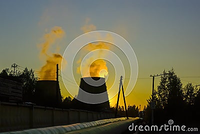 Smoke from huge pipes of city thermal power plant in sunset sky Stock Photo