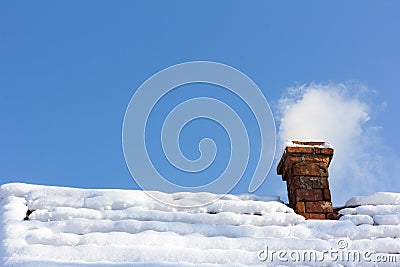 Smoke out of a brick chimney on a snowy rooftop Stock Photo