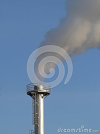 Smoke spews out of a chimney at an industrial plant Stock Photo