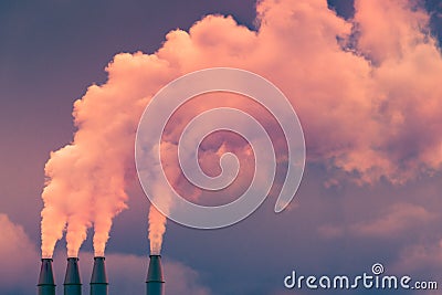 Smoke and steam rising into the air from power plant stacks; dark clouds background; concept for environmental pollution and Stock Photo