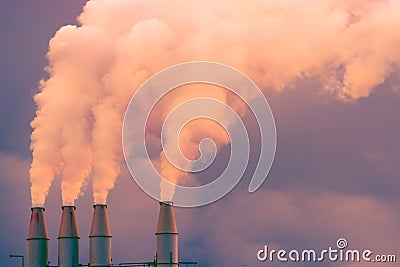 Smoke and steam rising into the air from power plant stacks; dark clouds background; concept for environmental pollution and Stock Photo