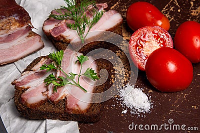 Smoked bacon with rye black bread and cuted tomatoes on the pack Stock Photo