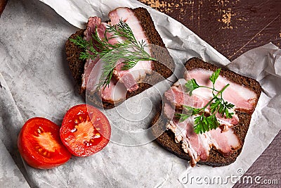 Smoked bacon with rye black bread and cuted tomatoes on the pack Stock Photo