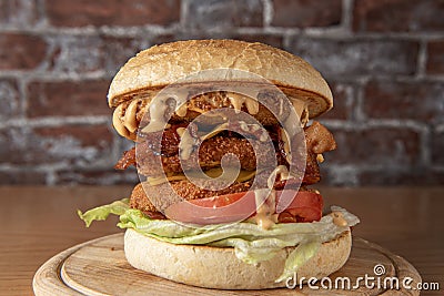 smoked chickenburger centred on wooden plate on dim wall background with bricks Stock Photo