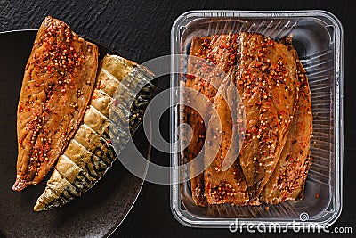 Smoked marinated mackerel fillet or fillet herring fish with spices packed in box on plate over slate stone background. Stock Photo