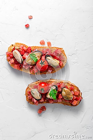 Smoked mussels on grilled bruschetta with tomatoes, white background, isolated Stock Photo