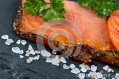 Smoked salmon slices and seasoning on natural black stone background Stock Photo
