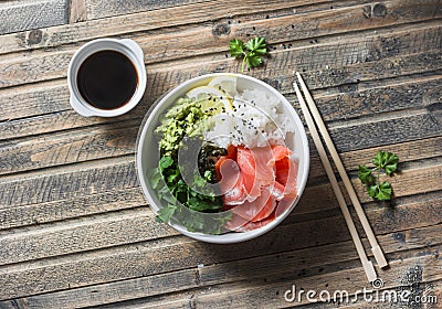 Smoked salmon sushi bowl on wooden background, top view. Rice, avocado puree, salmon - healthy food Stock Photo