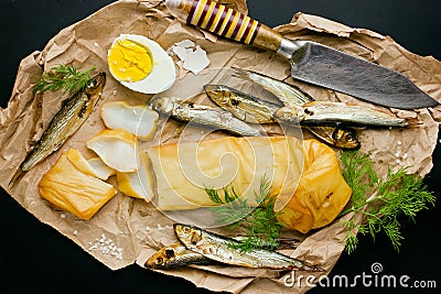 Smoked sprats and squid, boiled egg and fresh dill on paper Stock Photo