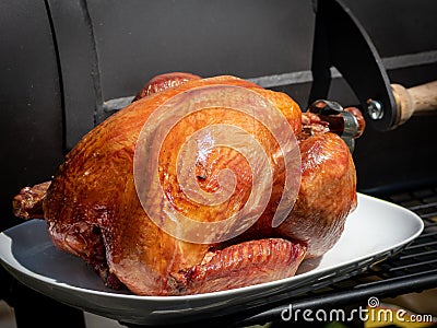 Smoked turkey on a white plate in front of a black smoker Stock Photo