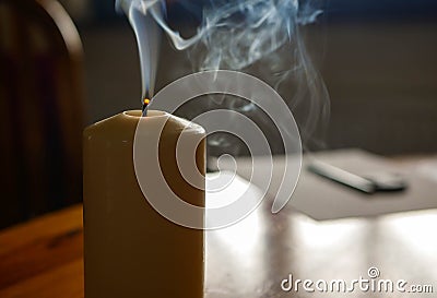 Smoking candle on wooden table after blowing off the flame Stock Photo