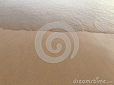 Smooth and clear brown sand beach with white sea waves Stock Photo