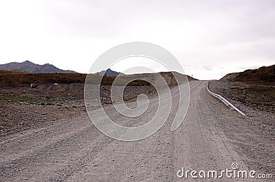 A smooth dirt road with a fence goes up the hill Stock Photo