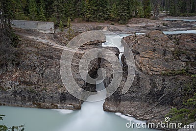 Smooth milky waters of a waterfall squeezing through a narrow rock opening in Jasper National Park, Canada Stock Photo