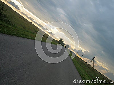 Smooth straight asphalt road in the countryside under the sky with clouds at sunset Stock Photo