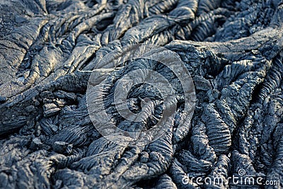 Smooth, undulating surface of frozen pahoehoe lava. Frozen lava wrinkled in tapestry-like folds and rolls resembling twisted rope Stock Photo