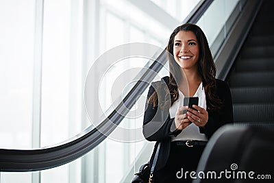 The smoothest business trip using the smartest apps. a businesswoman using a mobile phone while traveling down an Stock Photo