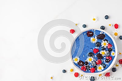 Smoothie bowl or nice cream made of blue spirulina, frozen berries, banana and coconut with chamomile flowers Stock Photo