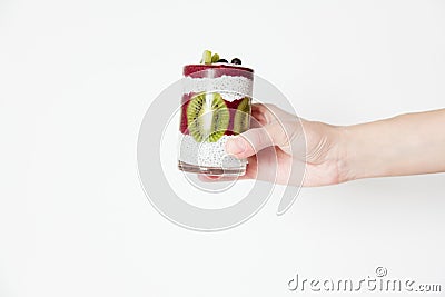 Smoothies in a glass in a hand on a white background with berries and fruits, blueberries, kiwi and chia seeds. Horizontal Stock Photo