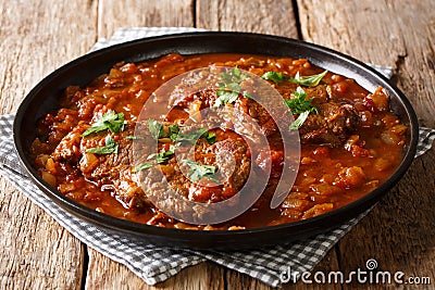 smothered beef steak cooked in tomato sauce with vegetables close-up. Horizontal Stock Photo