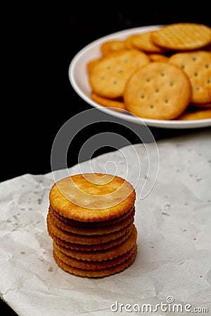 Snack concept, Salty crackers or biscuits arranged in vertical row on paper and heap on white plate Stock Photo