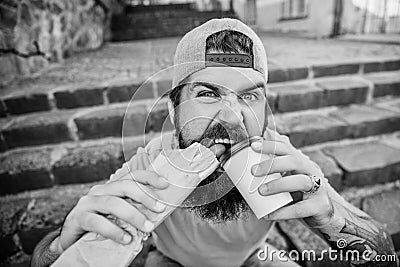 Snack for good mood. Guy eating hot dog. Street food concept. Man bearded eat tasty sausage and drink paper cup. Urban Stock Photo