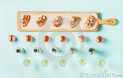 Snacks, brushettas, gazpacho shots, desserts, champagne over pastel blue background Stock Photo