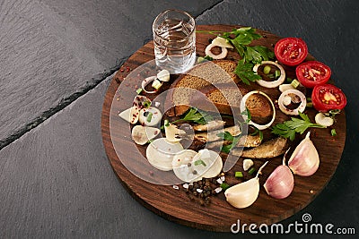 Snacks salted herring with fresh vegetables, onion, bread, sprats and shot of vodka Stock Photo